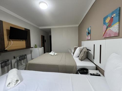 een kleine kamer met 2 bedden en een televisie bij Ponta Negra Beach Melo Flat in Natal