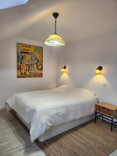 een witte slaapkamer met een groot bed en een lamp bij La suite signature in Maisonnais