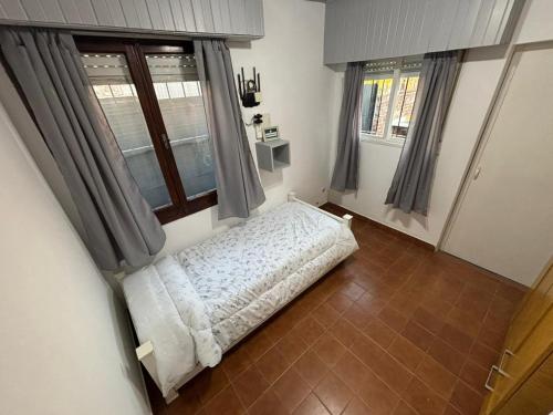 ein Schlafzimmer mit einem Bett und zwei Fenstern in der Unterkunft Casa necochea in Necochea