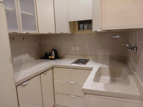 a kitchen with white cabinets and a sink at سفن روز للشقق المخدومة in Rabba