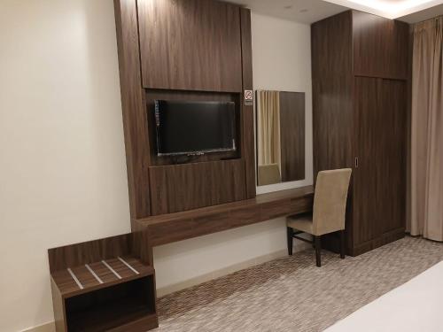 a hotel room with a tv and a chair in a room at سفن روز للشقق المخدومة in Rabba
