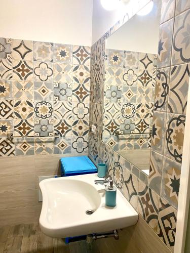 a bathroom with a sink and a tile wall at B&B le TRE CHIOCCIOLE in SantʼAntìoco