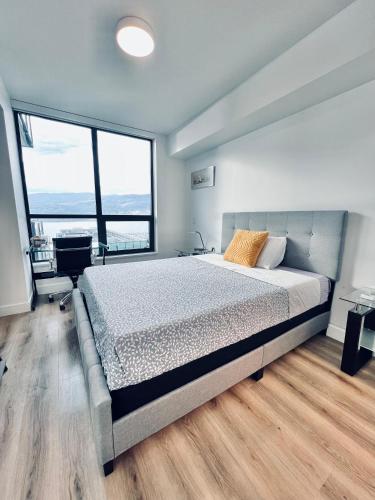 a bedroom with a large bed and large windows at Stunning Lake Views - downtown 2 Bedroom apartment - rooftop lounge in Kelowna