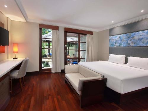 a bedroom with a large white bed and a desk at Novotel Bali Nusa Dua in Nusa Dua