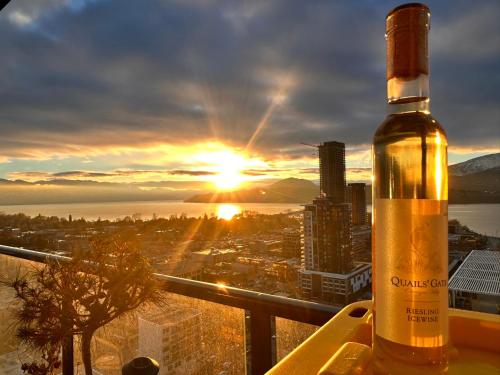 a bottle of wine sitting on a ledge with the sunset at Stunning Lake Views - downtown 2 Bedroom apartment - rooftop lounge in Kelowna