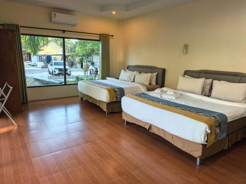 zwei Betten in einem Zimmer mit großem Fenster in der Unterkunft OYA International Resort Phuket 普吉岛欧雅国际度假酒店 in Phuket
