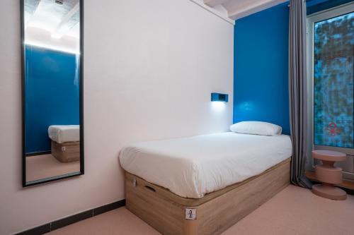 a small bedroom with a bed and a mirror at Malacuna Barcelona in Barcelona