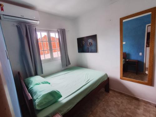 ein kleines Schlafzimmer mit einem Bett und einem Spiegel in der Unterkunft Casa de Praia Maresias in São Sebastião
