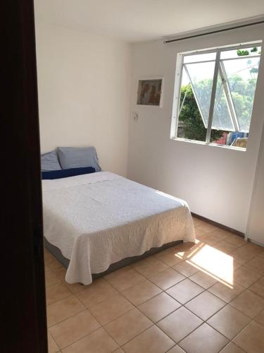a white bedroom with a bed and a window at Apto jaraguá lindo in Maceió