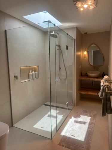 a bathroom with a glass shower with a sink at Mellow mountains, boutique beach house in Portarlington