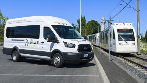 a white van is parked next to a train at Radisson Hotel Portland Airport in Portland