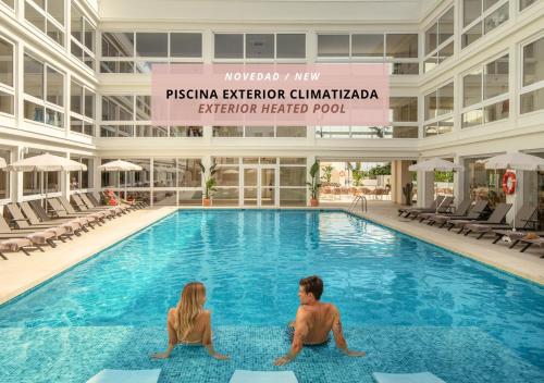 RH Silene Hotel & Spa 4 Sup في كاستيون دي لا بلانا: رجل وامرأة يجلسان في حمام السباحة