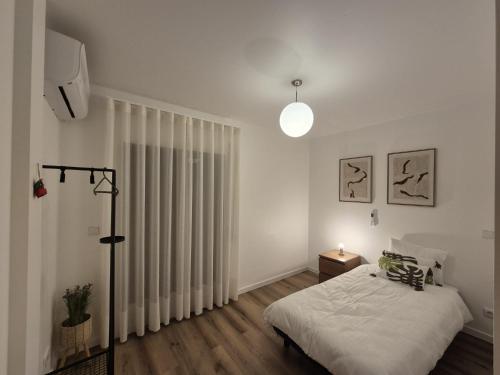 ein weißes Schlafzimmer mit einem Bett und einem großen Fenster in der Unterkunft Downtown apartment - Terrace, garage and pool in Olhão