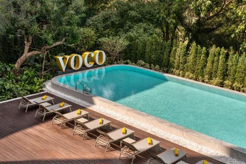 a swimming pool with lounge chairs and a sign at voco Bangkok Surawong by IHG in Bangkok