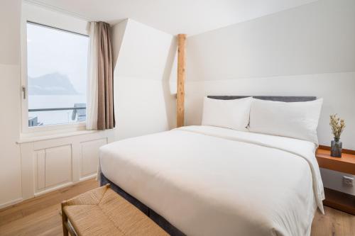 a bedroom with a large white bed with a window at Apartments Quellenhöfli in Vitznau