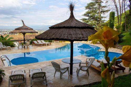 een zwembad met een tafel en stoelen en een parasol bij Portezuelo Hotel in Salta