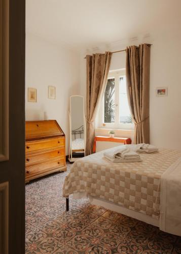 a bedroom with a bed and a dresser and a window at Ampelaki Blue in Paleokastritsa