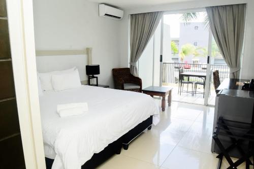 a bedroom with a bed and a balcony with a table at Margate Hotel in Margate