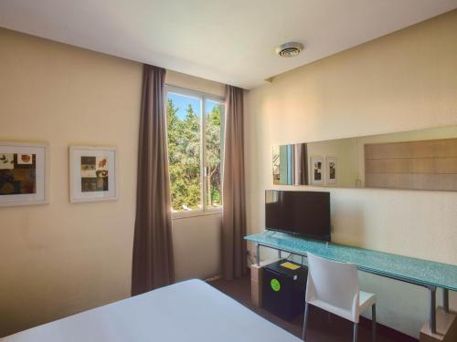 een slaapkamer met een bureau, een spiegel en een raam bij B&B HOTEL Calenzano First in Calenzano