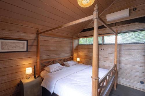 een slaapkamer met een bed in een houten kamer bij Mila Villa in Ngingas
