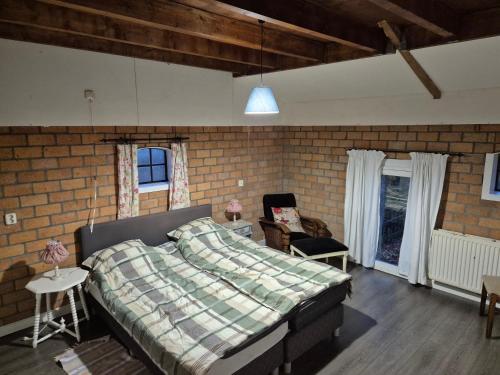 een slaapkamer met een bed en een bakstenen muur bij Hoeve Op Vollenhof in Wezep