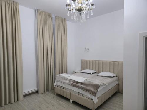a bedroom with a bed and a chandelier at Vila BELVEDERE in Brăila