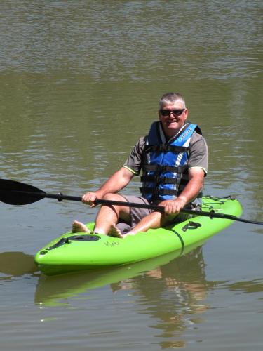 a man sitting on a green kayak in the water at Boomerang Way Tourist Park in Tocumwal