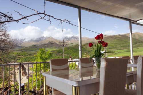 une table avec des roses rouges sur un balcon avec des montagnes dans l'établissement Aspet B&B in Tatev, à Tatev