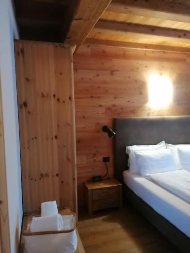 een slaapkamer met een bed en een houten wand bij Chalet Noemi in Livigno