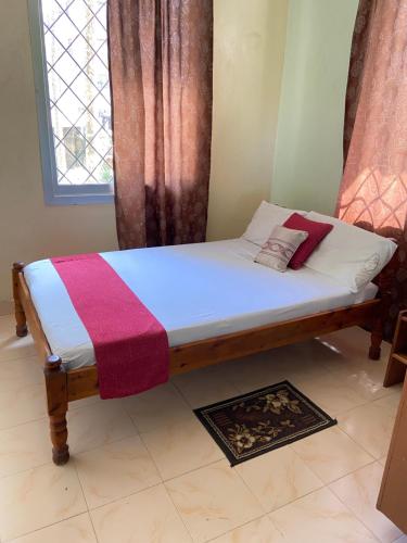 a small bed in a room with a window at Karmo Suites in Mombasa