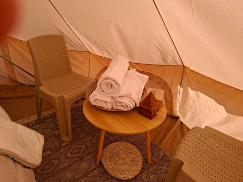ESCAPE cAMp في Badīyah: طاولة عليها منشفة وكرسي في خيمة