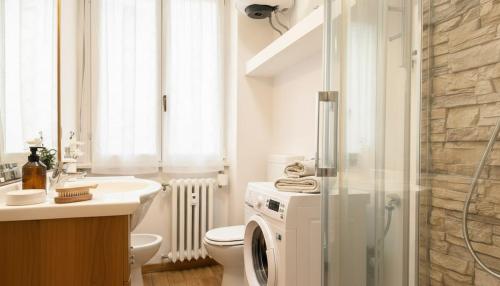 a bathroom with a toilet and a washing machine at Fiume 34 - bilocale luminoso e moderno a Sondrio in Sondrio