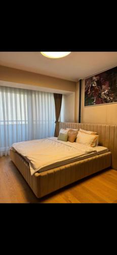 a bedroom with a large bed with white sheets and pillows at The Gallery Apartment in Prishtinë