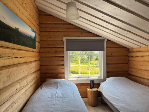 two beds in a log cabin with a window at The Moose Lodge Swedish Nature Retreat in Bräcke