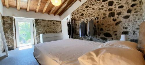 een slaapkamer met een wit bed in een kamer met stenen muren bij Casa Branca AL in Monchique