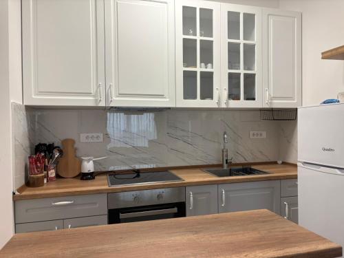 una cucina bianca con mobili bianchi e un lavandino di RIO Apartment a Petrovec