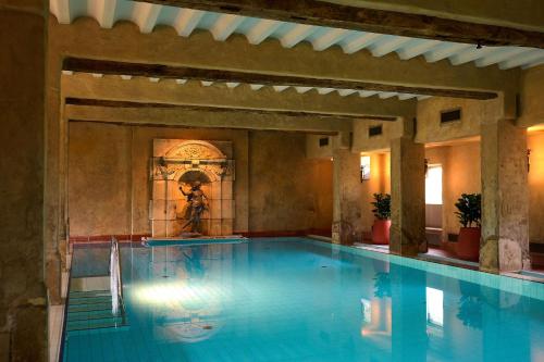 a large swimming pool with a fountain in a building at Château St Gerlach - Oostwegel Collection, member of Relais and Châteaux in Valkenburg