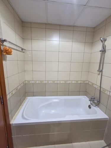 a bath tub in a tiled bathroom with a shower at Skycourts - Well furnished Studio apartment in Dubai
