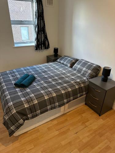 a bedroom with a bed with a plaid blanket and a window at Stunning Apartments Central Croydon in Croydon