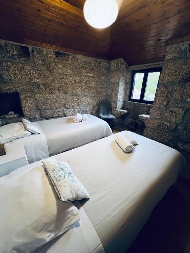 a bedroom with two beds and a stone wall at Retiro de Várzeas . Casa de Turismo Rural in Vieira do Minho