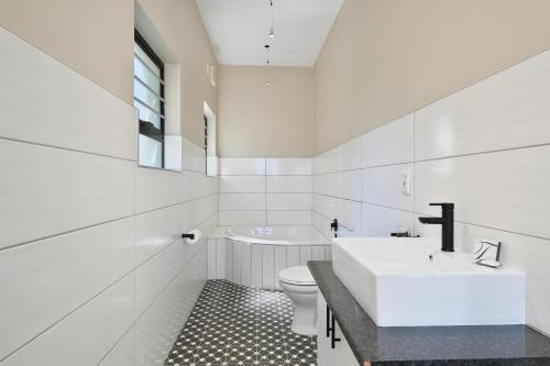 a white bathroom with a sink and a toilet at Ahoy Boutique Hotel in Gqeberha