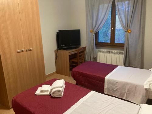 a hotel room with two beds and a television at La Villa Di Zio Pino in Camerino