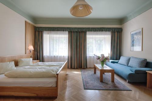 1 dormitorio con 1 cama y 1 sofá azul en Hotel Post, en Großkirchheim