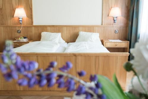 a bedroom with a bed with two lamps and purple flowers at Hotel Post in Großkirchheim