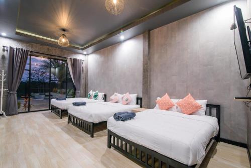 a bedroom with two beds and a flat screen tv at บ้านบรรยากาศ พูลวิลล่าชะอำ in Ban Bo Prakhon