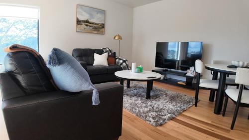 a living room with a black couch and a tv at Howick Heights Unit 3, Inner Launceston Living in Launceston