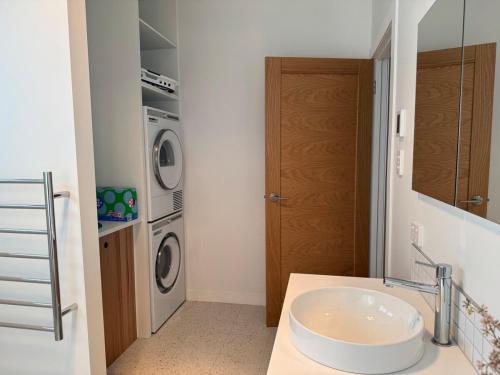 a bathroom with a sink and a washer and dryer at Howick Heights Unit 3, Inner Launceston Living in Launceston