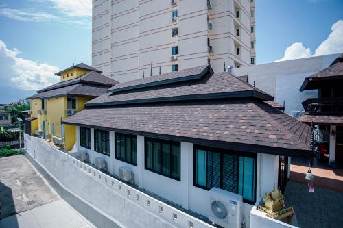 a building with a shingle roof next to a tall building at De Thaphae Chiangmai in Chiang Mai