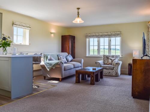 een woonkamer met een bank en een tafel bij The Stables in Whissendine