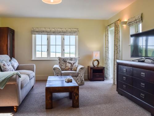 een woonkamer met een bank en een tv bij The Stables in Whissendine